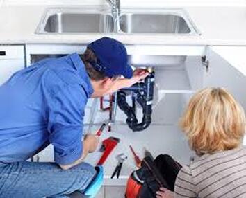 plumber with customer under sink